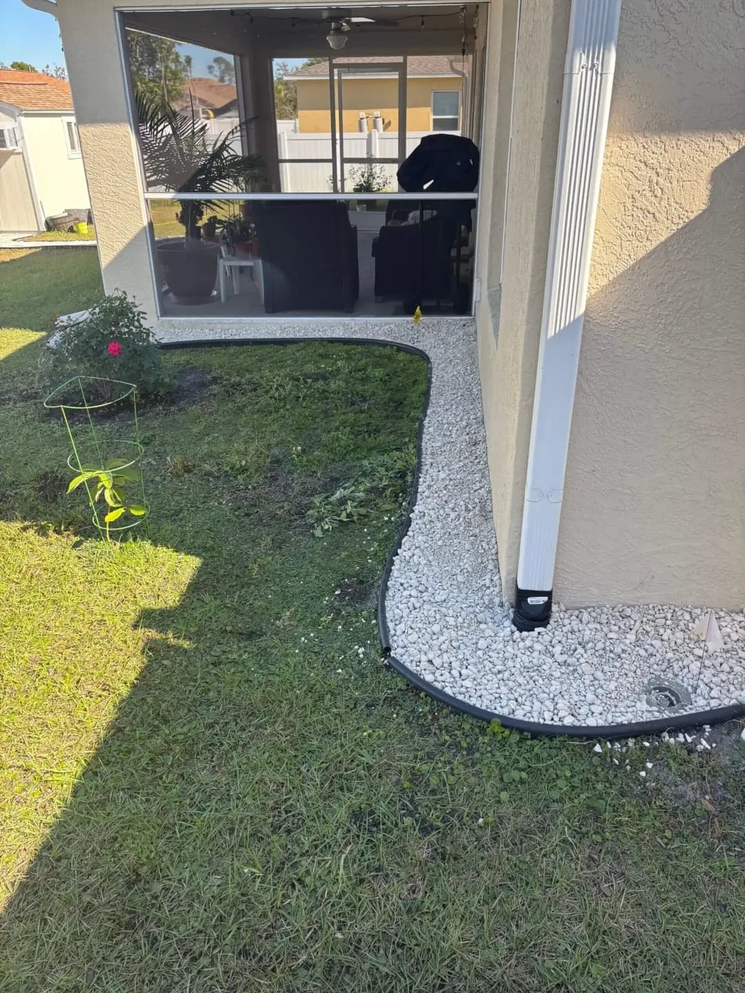 Clean white rock border along the back of a screened lanai
